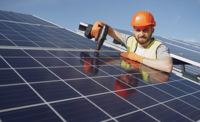 Photo d'un artisan qui installe des panneaux solaires
